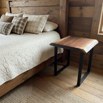 Handcrafted solid wood live edge nightstand in walnut color beside rustic wood bed with plaid bedding