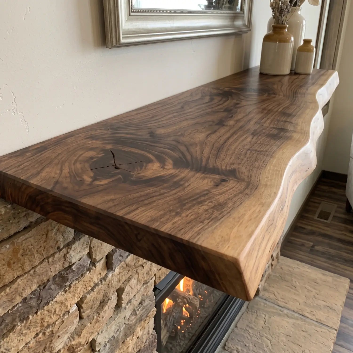 Close-up of a solid wood live edge mantel shelf above a stone fireplace with decorative vases and visible wood grain