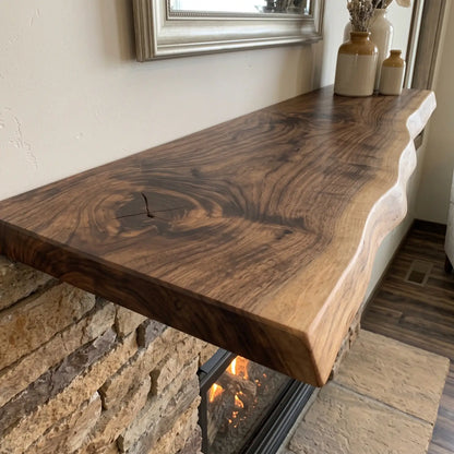 Close-up of a solid wood live edge mantel shelf above a stone fireplace with decorative vases and visible wood grain