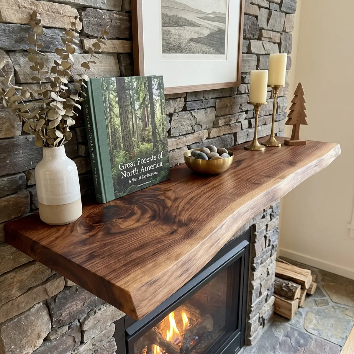 Live edge wood fireplace mantel shelf styled with a book, bowl, candles and vase over a stone fireplace surround