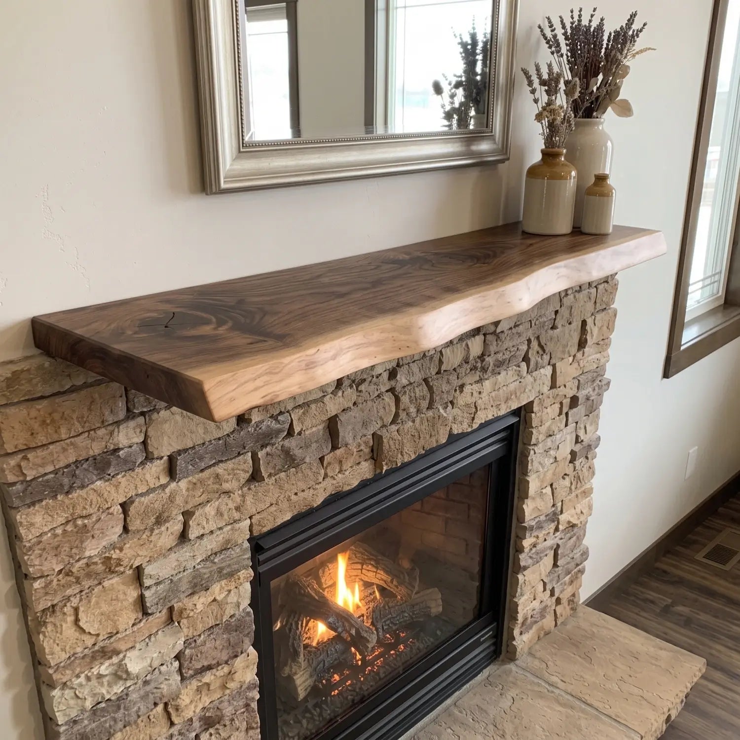 Live edge solid wood floating mantel installed over a stone fireplace with mirror and neutral vase decor