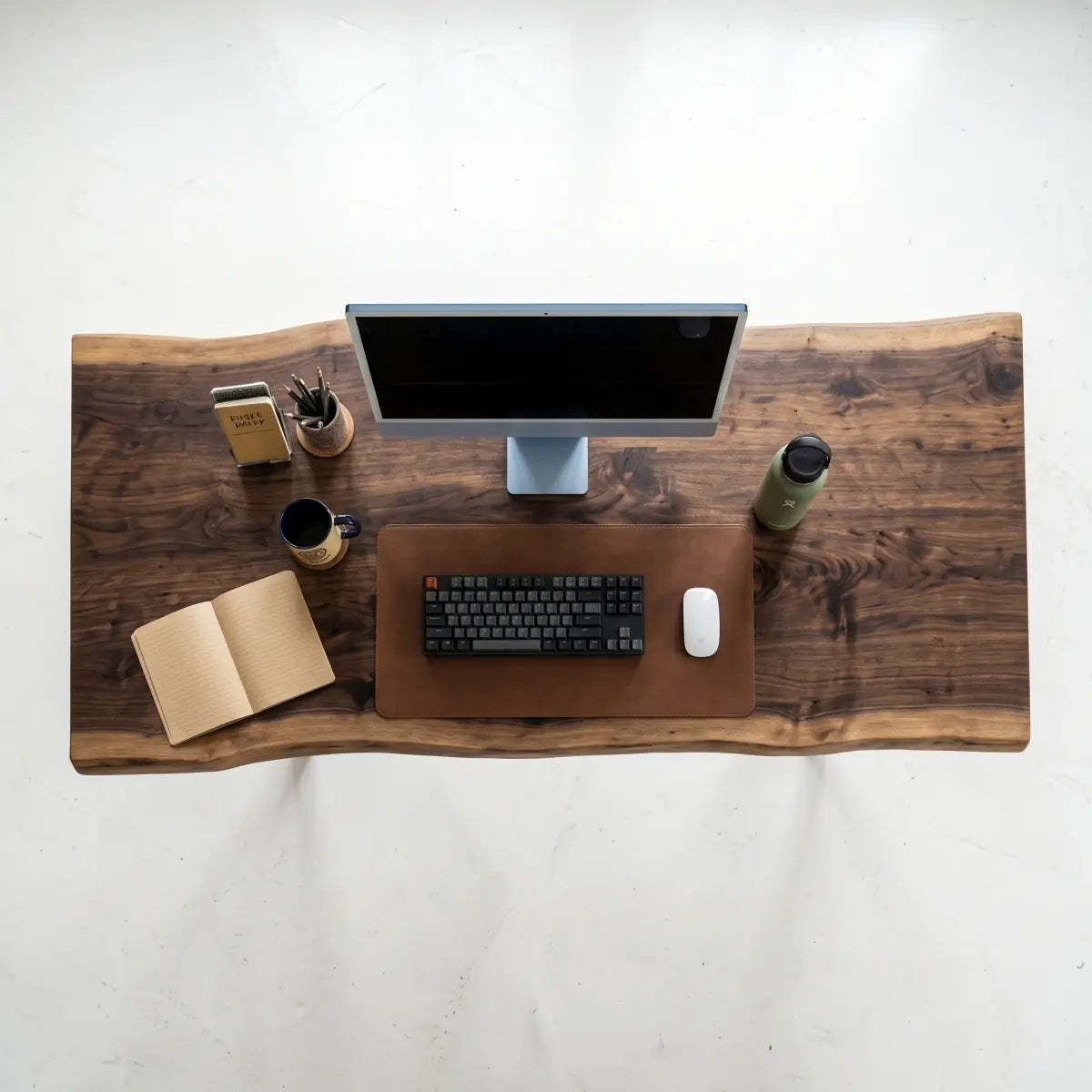 Top view of solid wood live edge office desk with monitor, keyboard and desk accessories