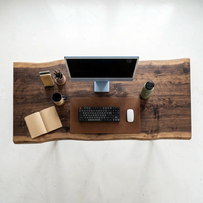 Top view of solid wood live edge office desk with monitor, keyboard and desk accessories