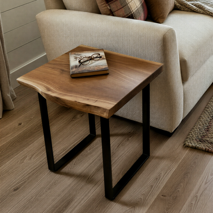 Compact solid wood live edge side table in walnut color finish beside light-colored sofa, styled with small decor