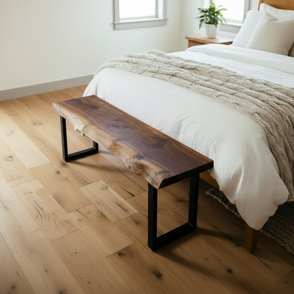 Solid wood live edge bench in walnut finish placed at the foot of a bed with light wood flooring