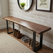 Solid wood live edge bench in walnut color with black steel legs in an entryway, shoes underneath, round mirror on wood panel wall