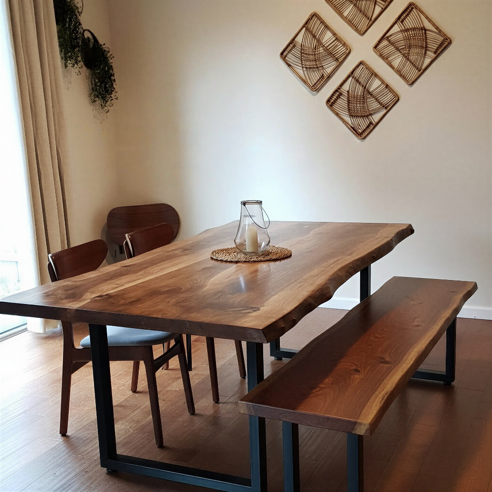 Solid wood live edge dining table and bench in walnut color with black steel legs, warm lighting and cozy